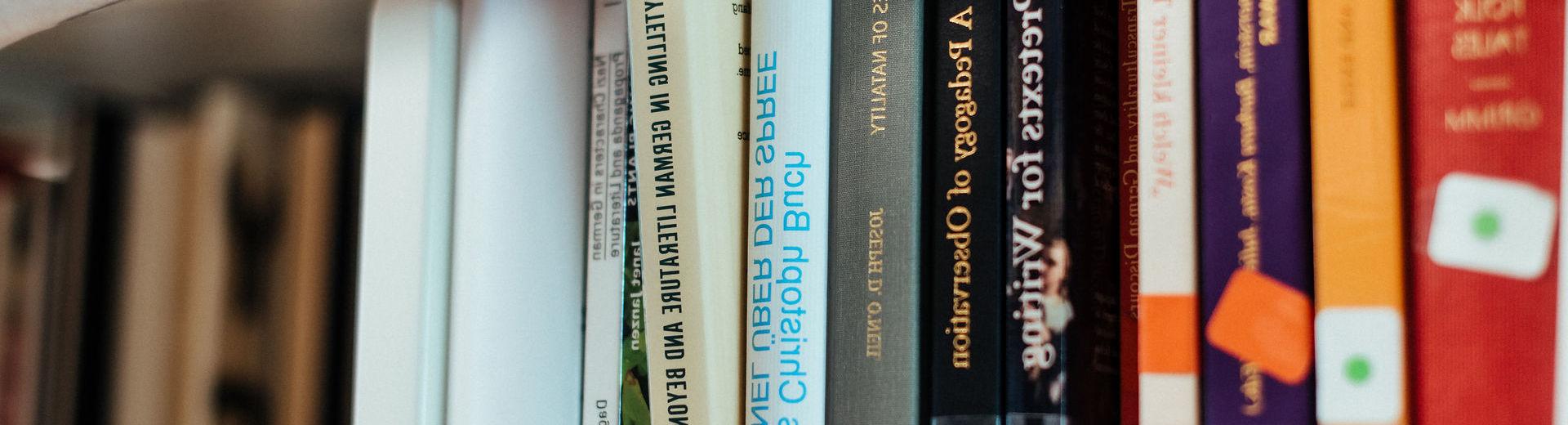 Close up of a hand choosing a book on storytelling on a shelf in the stacks.